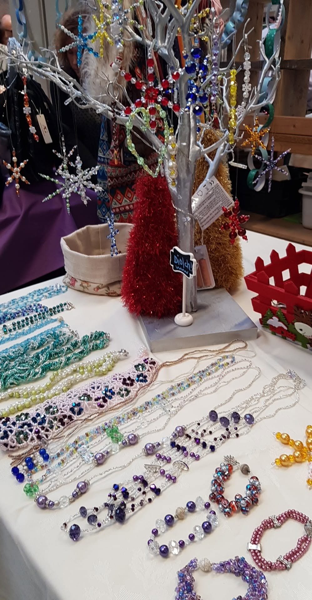 Purple, blue and green beaded necklaces and bracelets on a craft stall