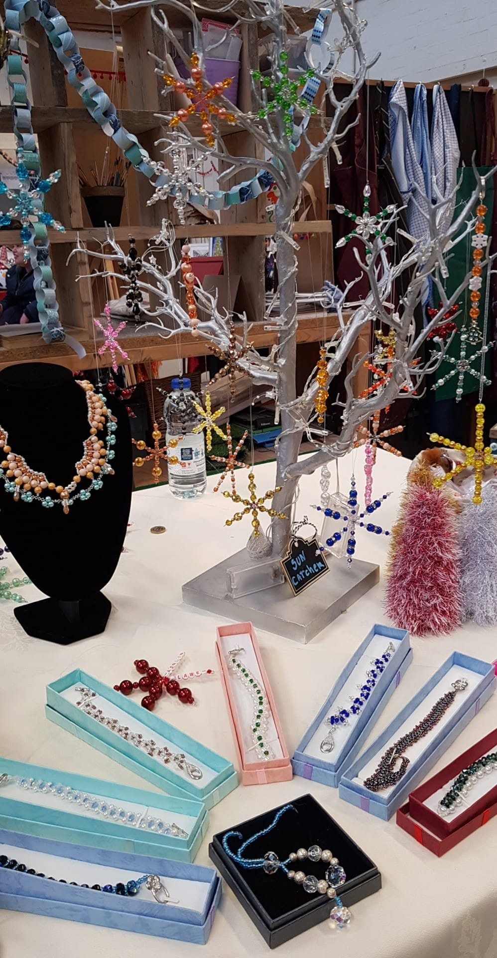Colourful beaded snowflakes and sun catchers hanging from a display tree